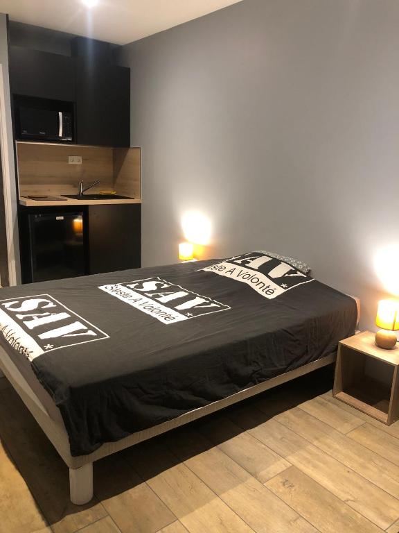- une chambre avec un lit et une couette noire dans l'établissement Mini Studio avec Terrasse, à Aurillac