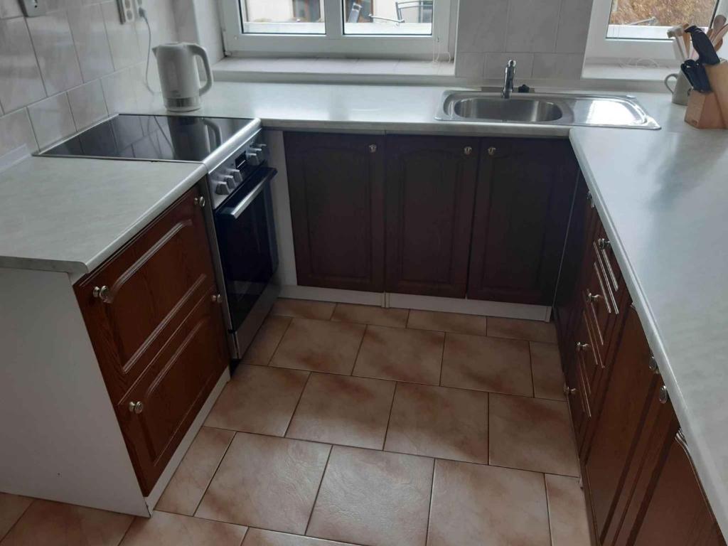 a kitchen with brown cabinets and a sink and a tile floor at Holiday home Pekov - Adrspach-Felsen 1432 in Pěkov