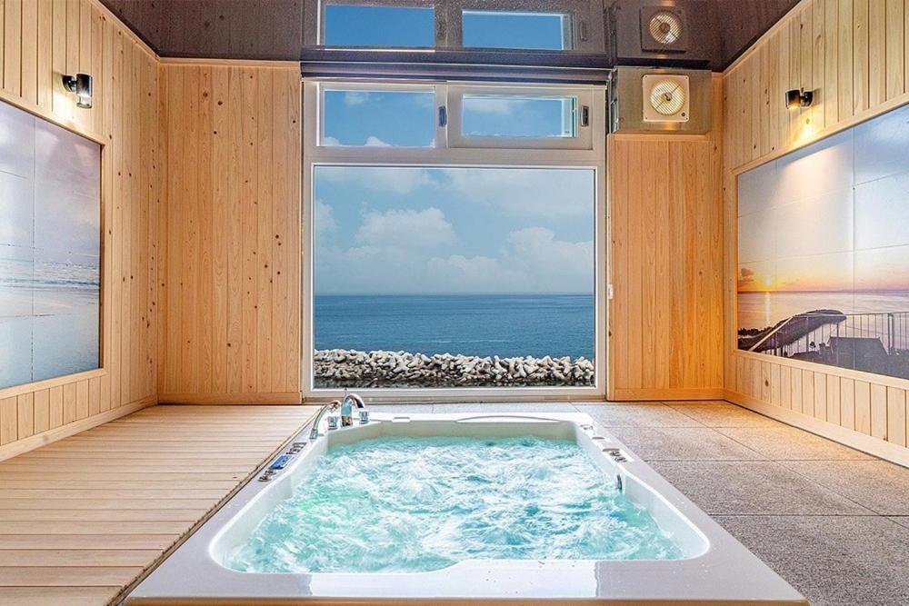 a bath tub in a room with a view of the ocean at Yeongdeok Hillington Hotel Resort Pension in Changsa-ri