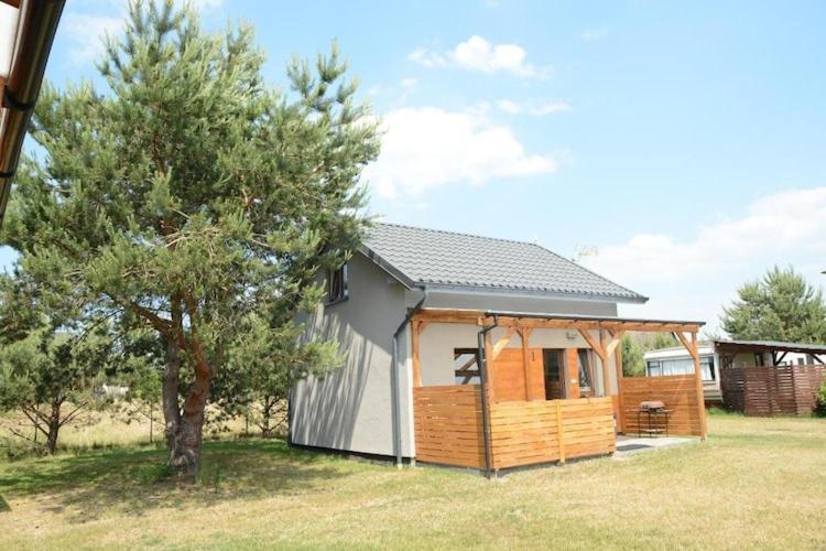 a small cabin with a tree in a field at Comfortable holiday home, sauna, fishing pond in Wodnica
