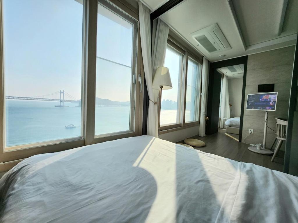 ein Schlafzimmer mit einem großen Bett mit einem großen Fenster in der Unterkunft Busan #Gwanganri #Full Ocean #Healing in Busan