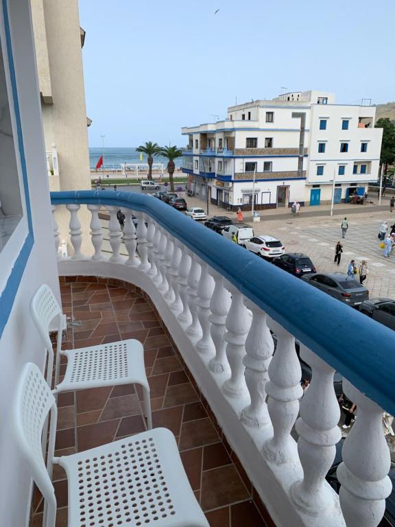 a balcony with two white chairs and a parking lot at Appartement confortable à mdiq in M'diq