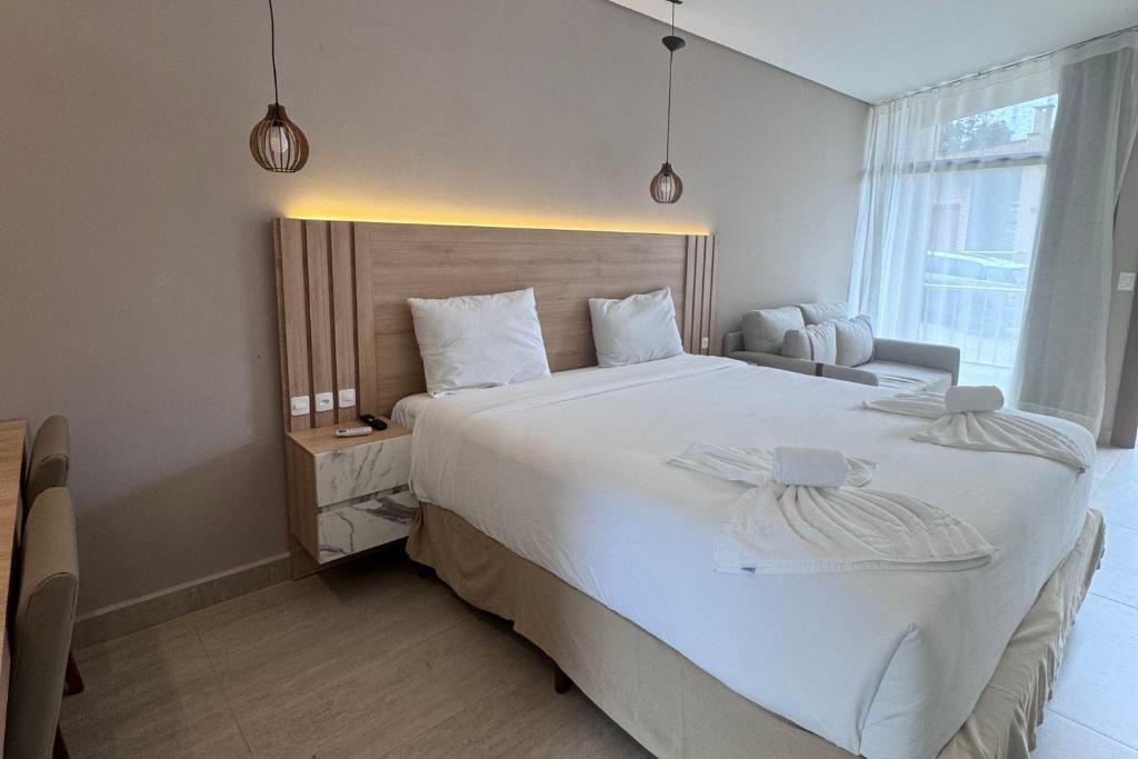 a bedroom with a large white bed and a window at Chalé para 4 pessoas in Campina Grande do Sul