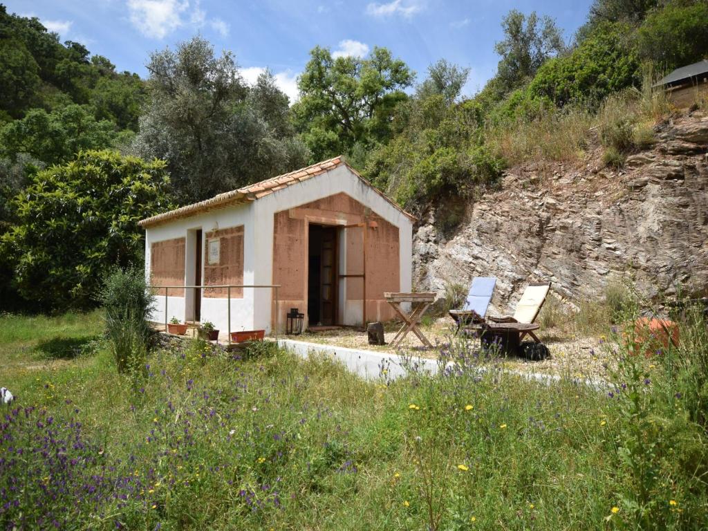 un piccolo edificio con una panchina e una sedia in un campo di Cottage in São Luís near Costa Vicentina a São Luis