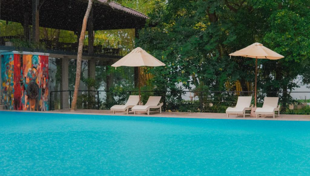 a group of chairs and umbrellas next to a swimming pool at Clio Bolgoda in Piliyandala