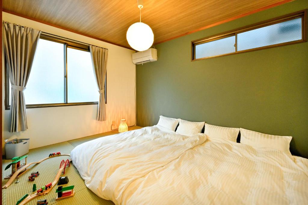 ein Schlafzimmer mit einem großen weißen Bett und Fenstern in der Unterkunft Takaoka House in Nagoya