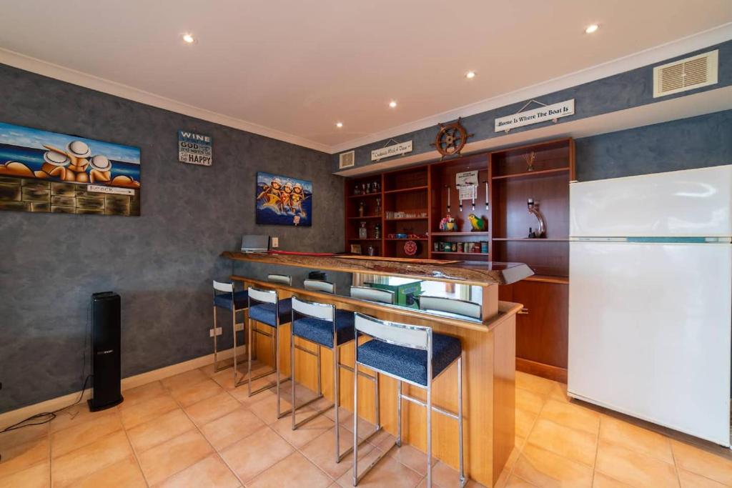 a kitchen with a bar and a refrigerator at Funland, Family Home On The Canals Mandurah in South Yunderup