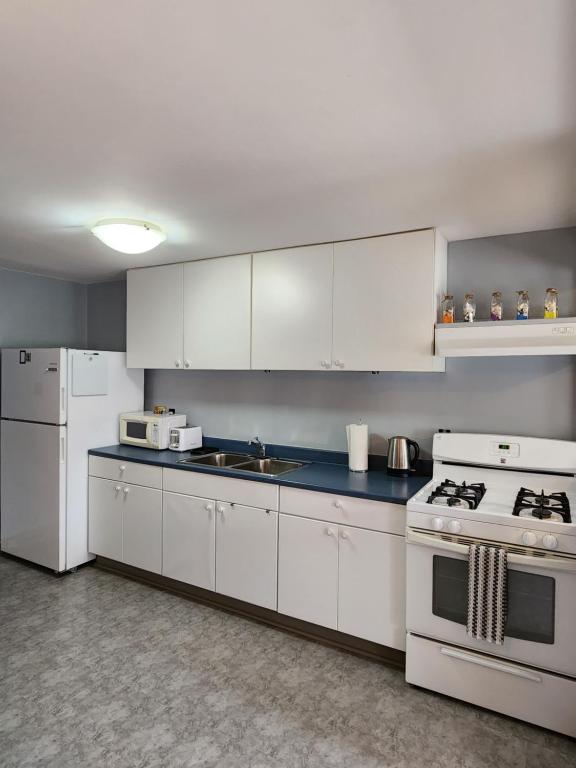 a kitchen with white cabinets and white appliances at Two bedroom apartment in Torbay in Torbay