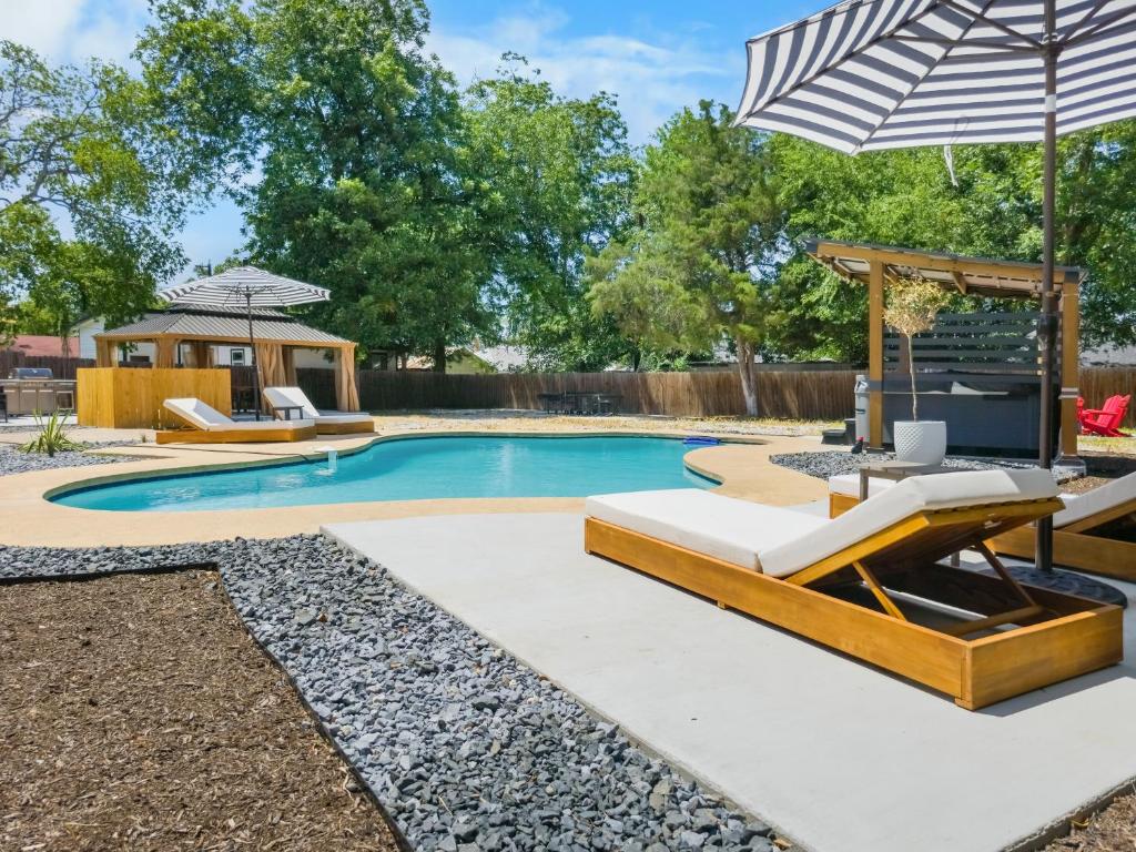 a swimming pool with lounge chairs and an umbrella at Spacious Retreat with Pool & Hot Tub - 10 Minutes to Downtown in San Antonio