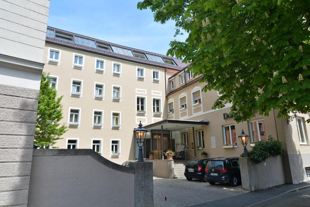 un gran edificio con coches estacionados frente a él en Dom Hotel, en Augsburg