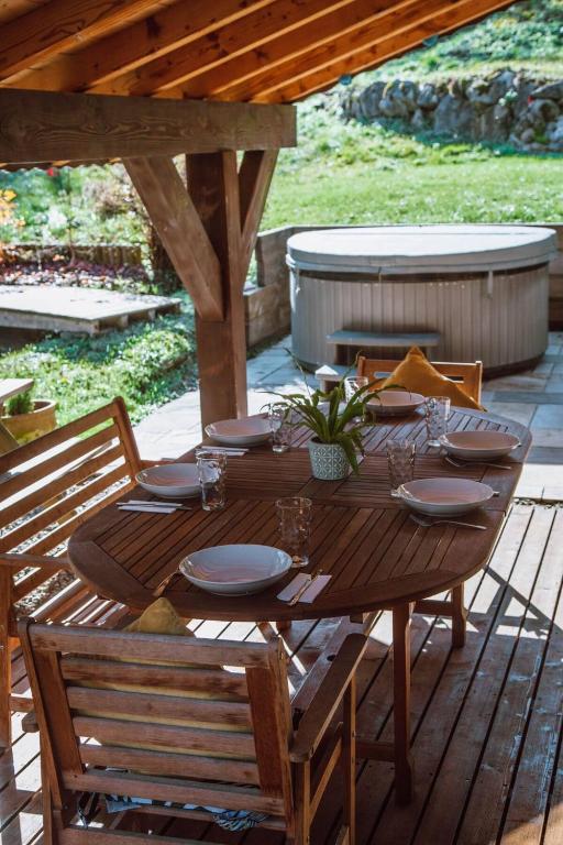 a wooden table with plates and glasses on a patio at Chalet Dranse skiVTT - Mountain Voyages chalet in Saint-Jean-d'Aulps