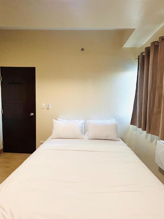 a bedroom with a large bed with white sheets at 11 Poolside Balcony Bliss in Iloilo City