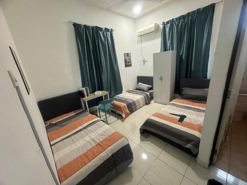 a room with three beds in it with green curtains at Taman Sri Utama Gurun 