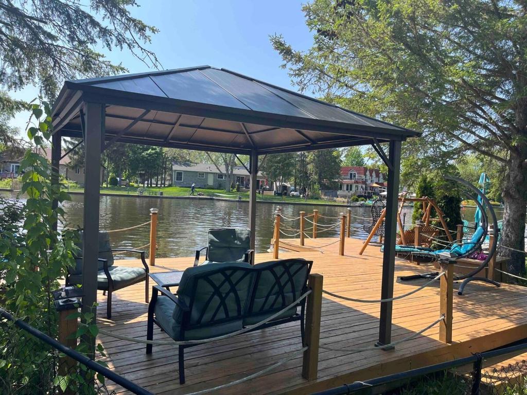a gazebo on a dock with chairs and a playground at Beautiful Four Bedroom Lagoon City Waterfront Home in Brechin