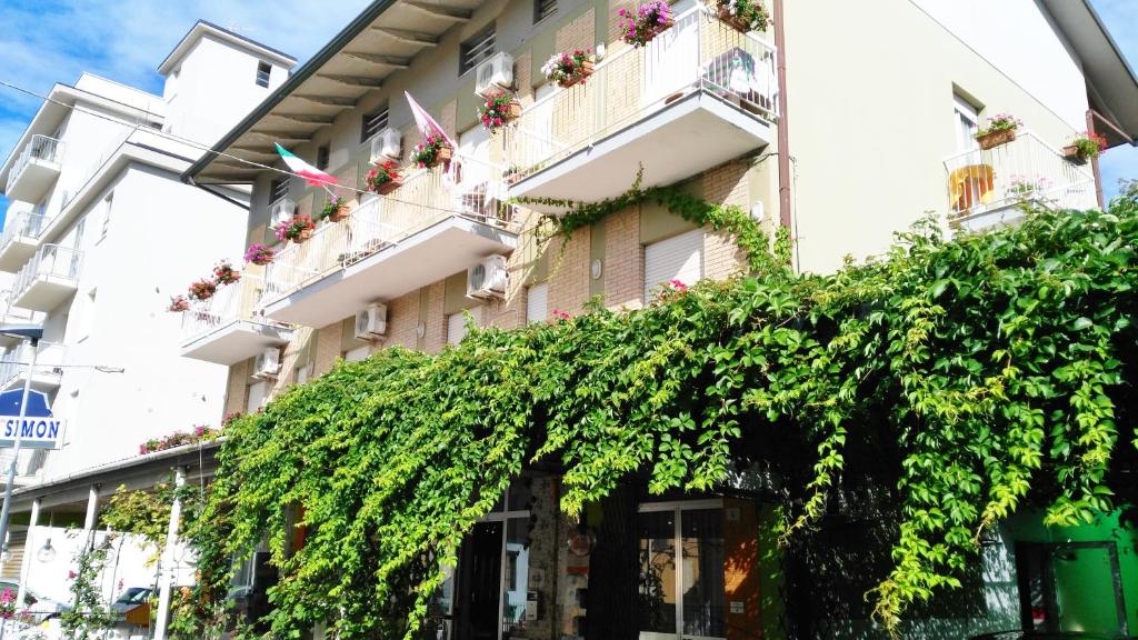 un edificio con una grande siepe verde davanti di Hotel Simon a Rimini