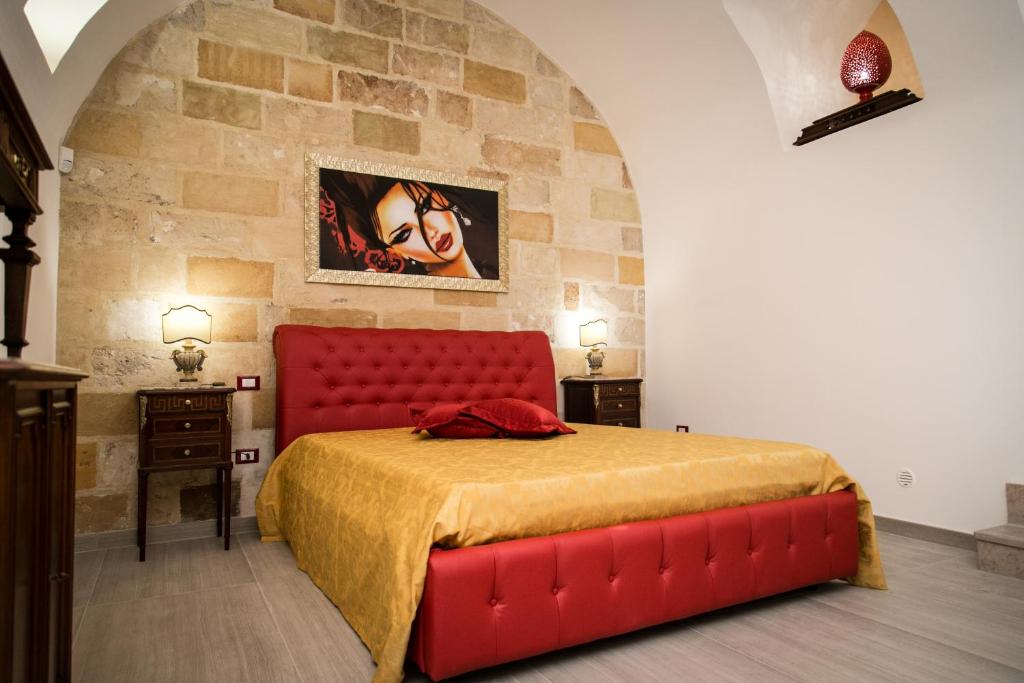 コペルティーノにあるCasa a Corteの赤いベッドと石の壁が備わるベッドルーム1室