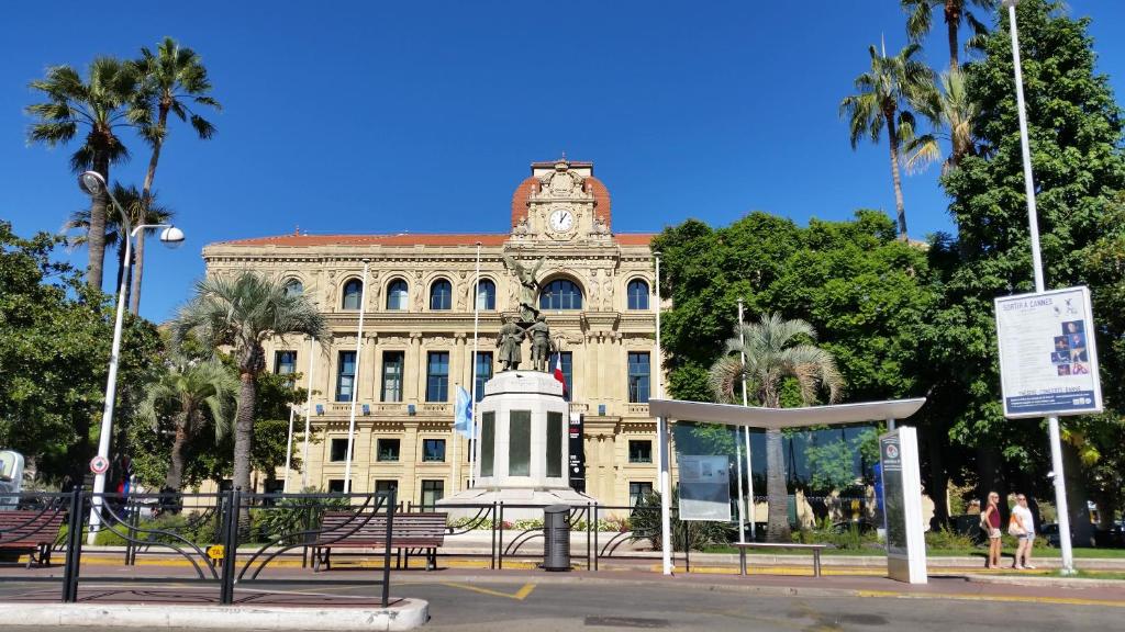 un edificio con una torre de reloj y una estatua delante en Chez Grace, en Cannes