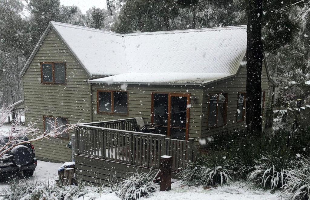 una pequeña casa con nieve en el techo en Blackwood Chalet, en Merrijig