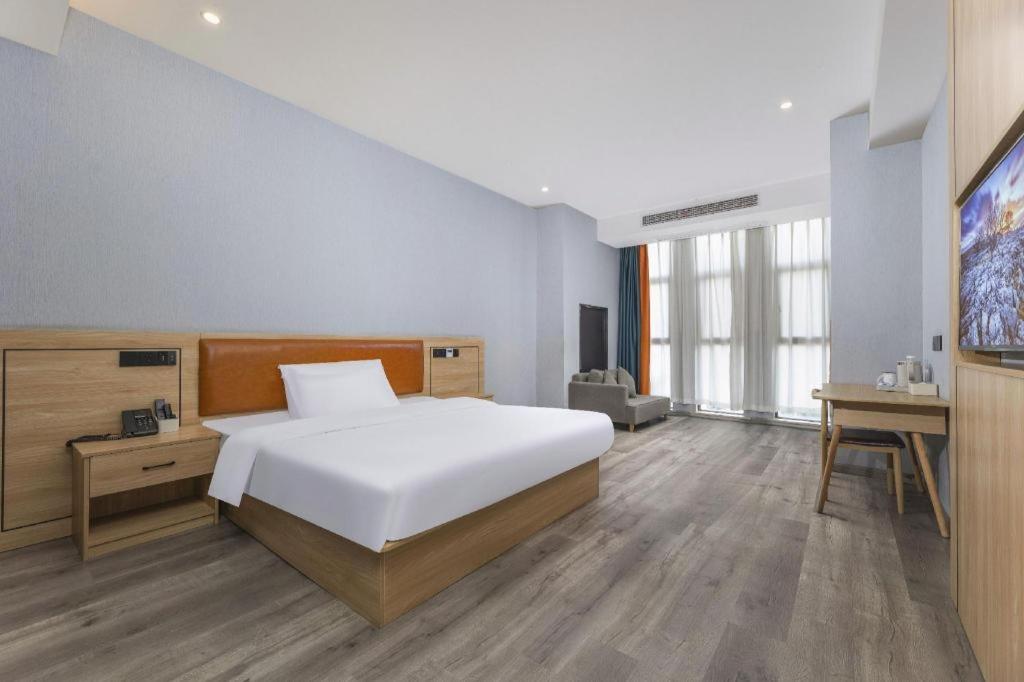 une chambre avec un grand lit blanc et un bureau dans l'établissement Borrman Hotel Jiangyin Zhouzhuang, à Xiwujieqiao