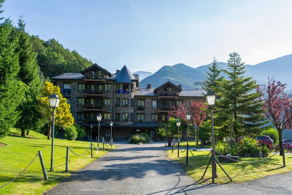 a large building with mountains in the background at Abba Xalet Suites Hotel in Sispony