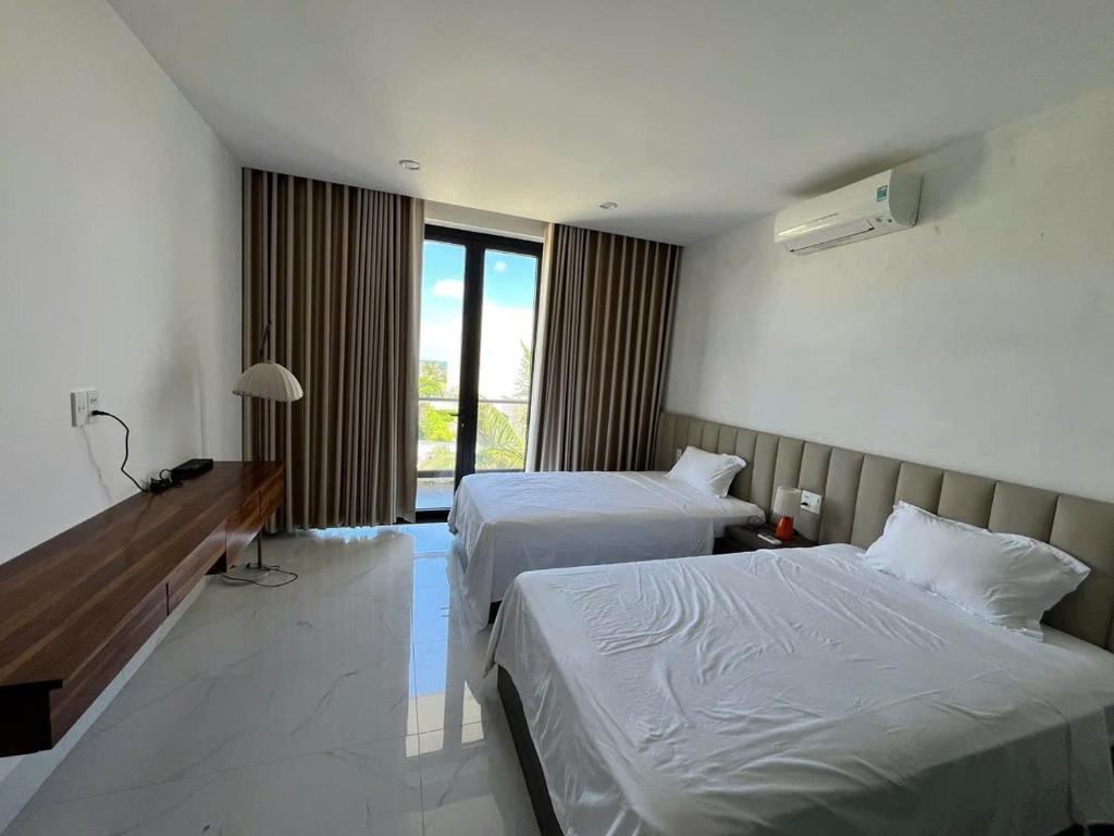 a hotel room with two beds and a window at Beach villas ideal for families & groups to get together & retreat in Ấp Phước Tĩnh