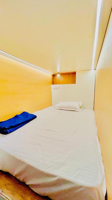 1 dormitorio con cama blanca y manta azul en LF Easybeds, en Kozhikode