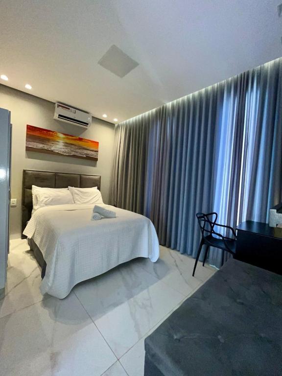 a bedroom with a white bed and a piano at Casa, 01 Suíte, Ar-Cond, Área Gourmet e Garagem Ampla in Montes Claros