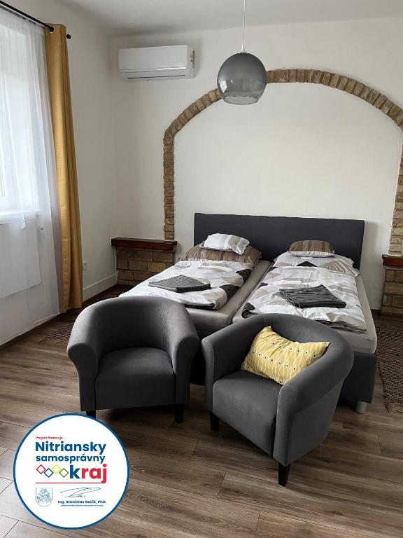 a bed and a chair in a room at Apartman - Garden - Vendégház in Nesvady