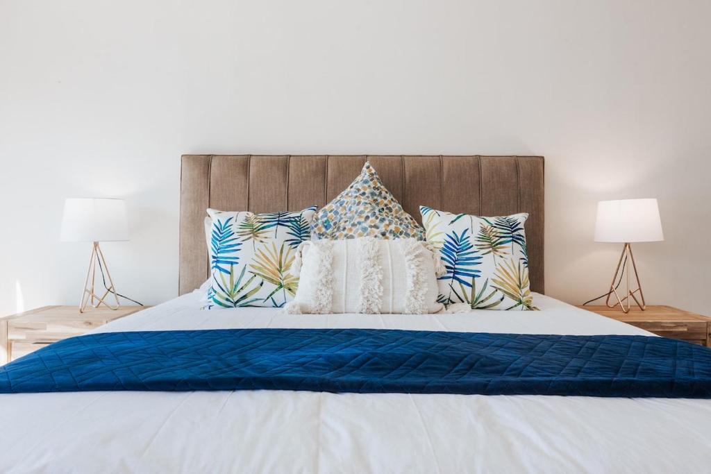 a bed with blue and white sheets and pillows at Green Parrot Holiday Apartment in Fish hoek