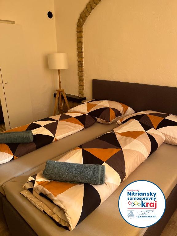 two beds in a hotel room with colorful blankets at Apartman - Garden - Vendégház 2 in Nesvady