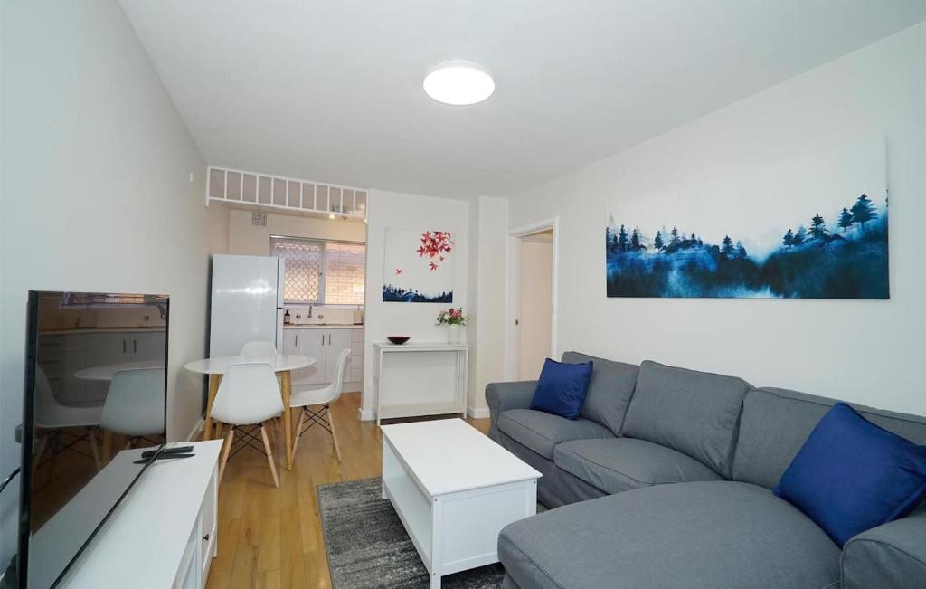 a living room with a gray couch and a kitchen at Rivervale Cosy Stunner Sleeps 2 in Perth