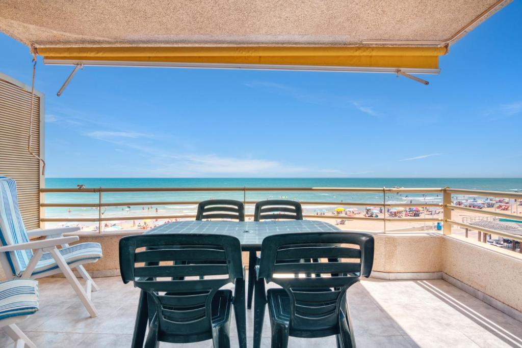 une table et des chaises sur un balcon avec vue sur la plage dans l'établissement Vistamar, à Bellreguart