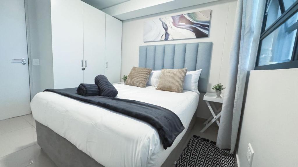 a bedroom with a white bed with a black blanket at Apartment in uMhlanga The Millennial in Durban