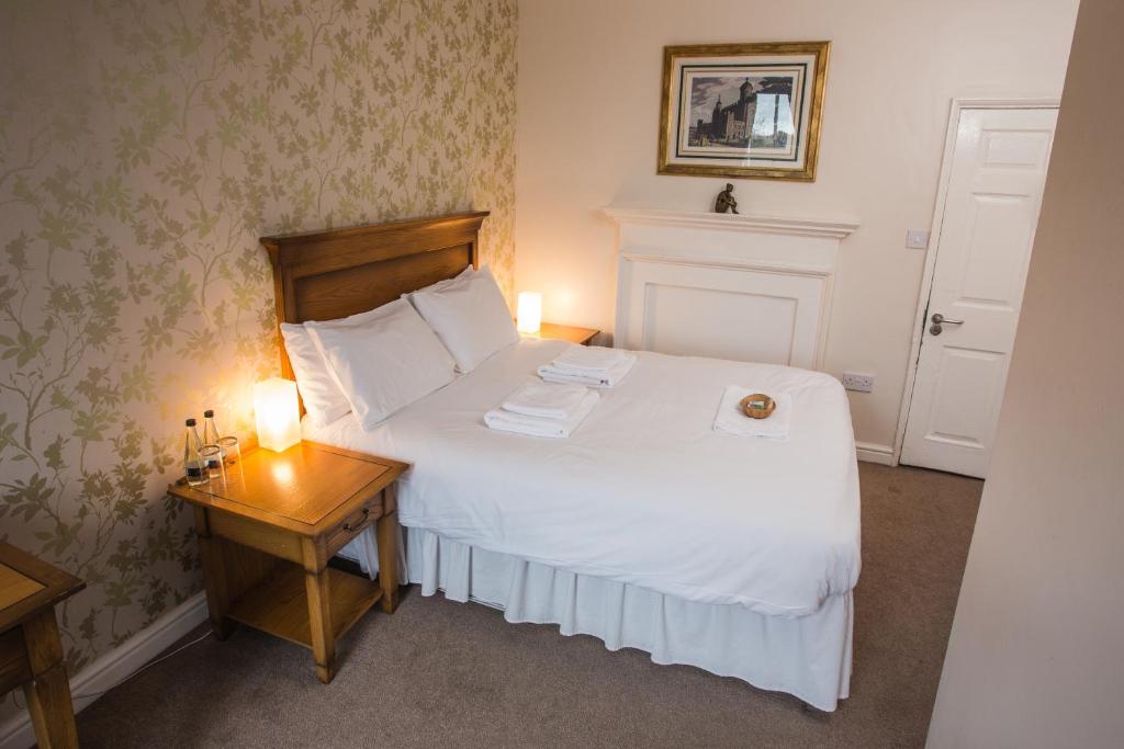 ein Schlafzimmer mit einem weißen Bett und einem Tisch mit Beleuchtung in der Unterkunft Waggon and Horses in York