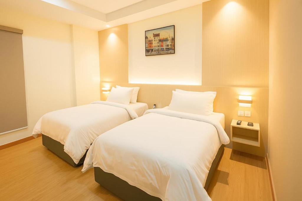 a hotel room with two beds with white sheets at Kawi Jaya Hotel in Nagoya