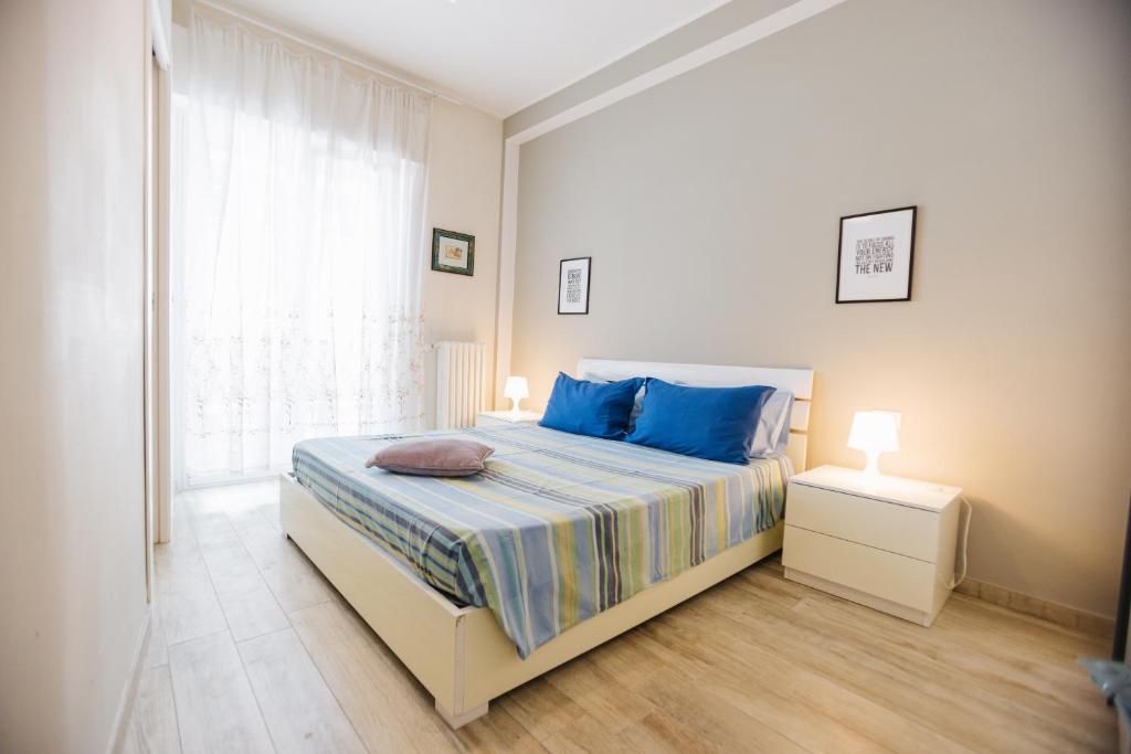 a bedroom with a bed with blue pillows and a window at Ampio appartamento in centro Pescaramare in Pescara