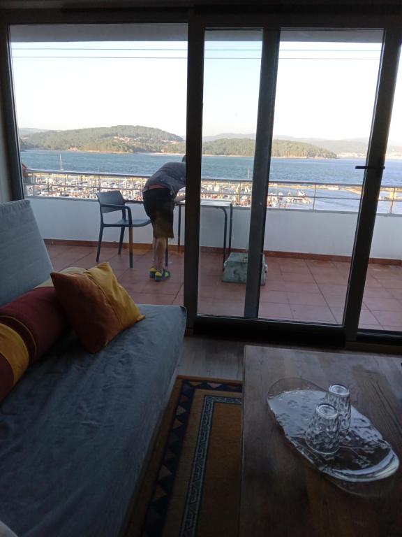 a person bending over in a living room with a large window at O Peirao in Siavo