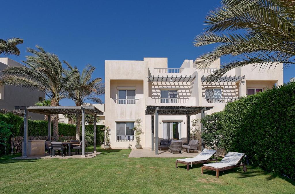 een groot wit gebouw met een tuin met banken bij VESTA - Gouna Residence in Hurghada
