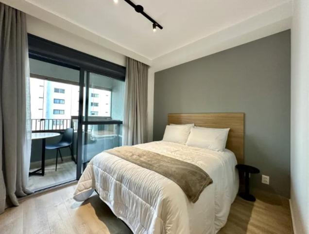 Un dormitorio con una cama y un balcón con una mesa. en Campo Belo Brand New Studio, en São Paulo