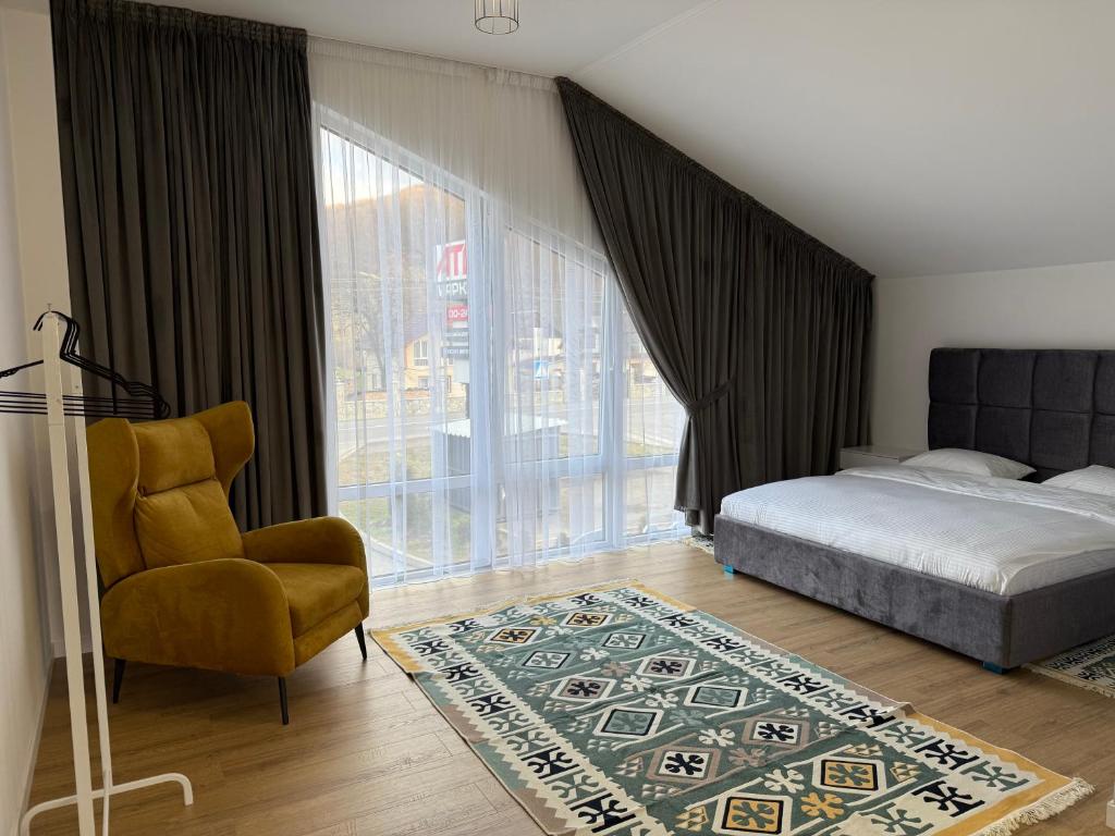a bedroom with a bed and a chair and a window at Yaremche Apartments in Yaremche