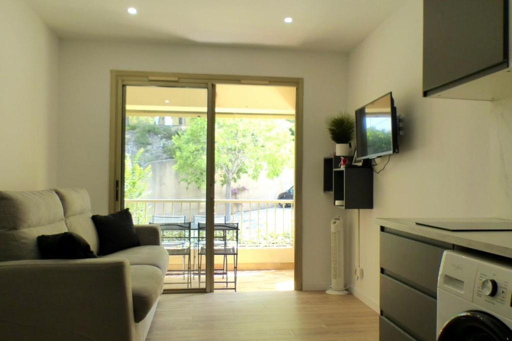 un salon avec un canapé et une télévision et un balcon dans l'établissement Studio with pool in the heart of Sanary-sur-Mer, à Sanary-sur-Mer