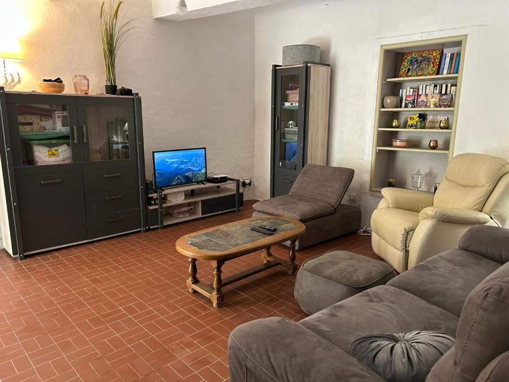 Una sala de estar con sofás, un televisor y una mesa. en Maison de vacances La Bastide des Poètes Tour du Couridou, en Venterol