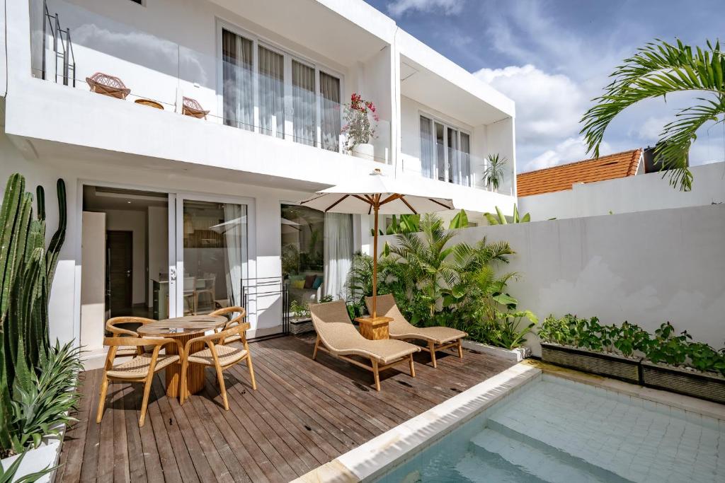 un patio avec une table et des chaises à côté d'une piscine dans l'établissement Casa Medjango Canggu, à Canggu