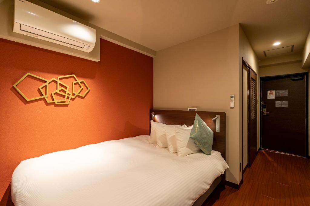 a bedroom with a white bed with an orange wall at Red Roof Inn Kamata / Haneda Tokyo in Tokyo