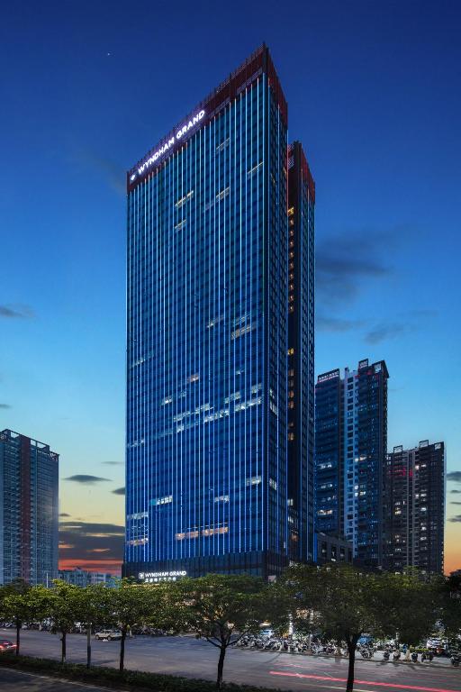 a tall building with blue windows in a city at Wyndham Grand Maoming in Maoming