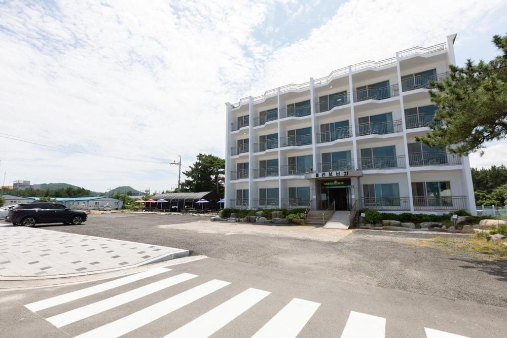 un gran edificio blanco con un coche aparcado delante de él en Olive Beach Pension, en Yangyang