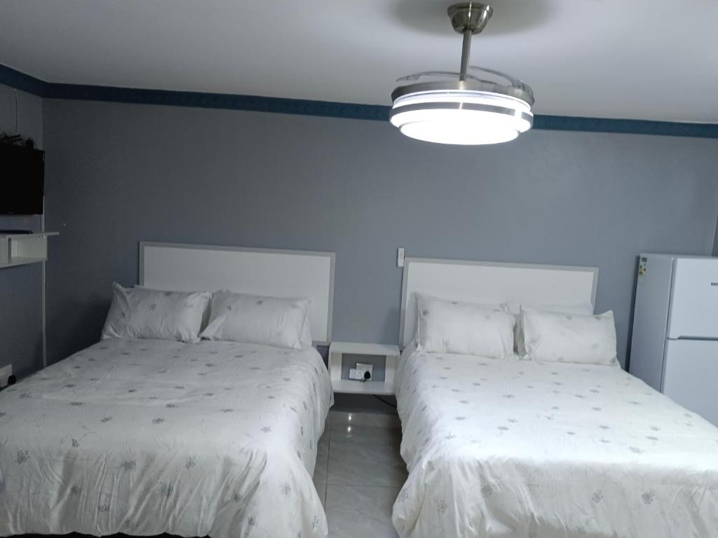 two beds in a room with white sheets at Crompton Studio Apartment 786 in Durban