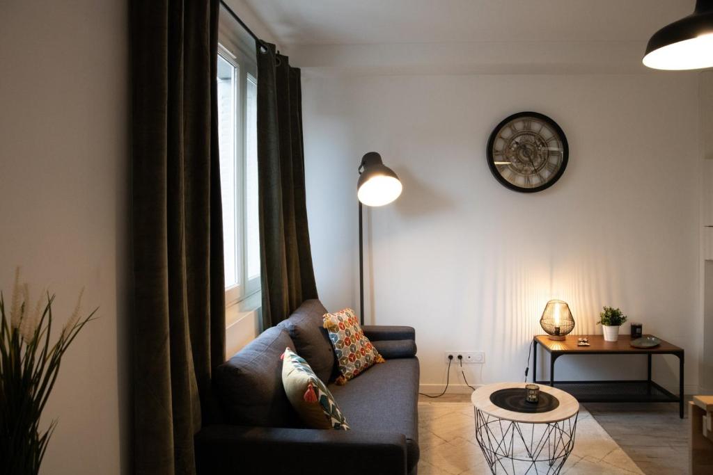 un salon avec un canapé et une horloge au mur dans l'établissement Le Bollier - Charmant appartement au calme, à Lyon