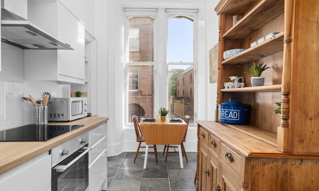 a kitchen with white cabinets and a small table at Steeple View Apartment - Cosy 1 bed in Montrose in Montrose