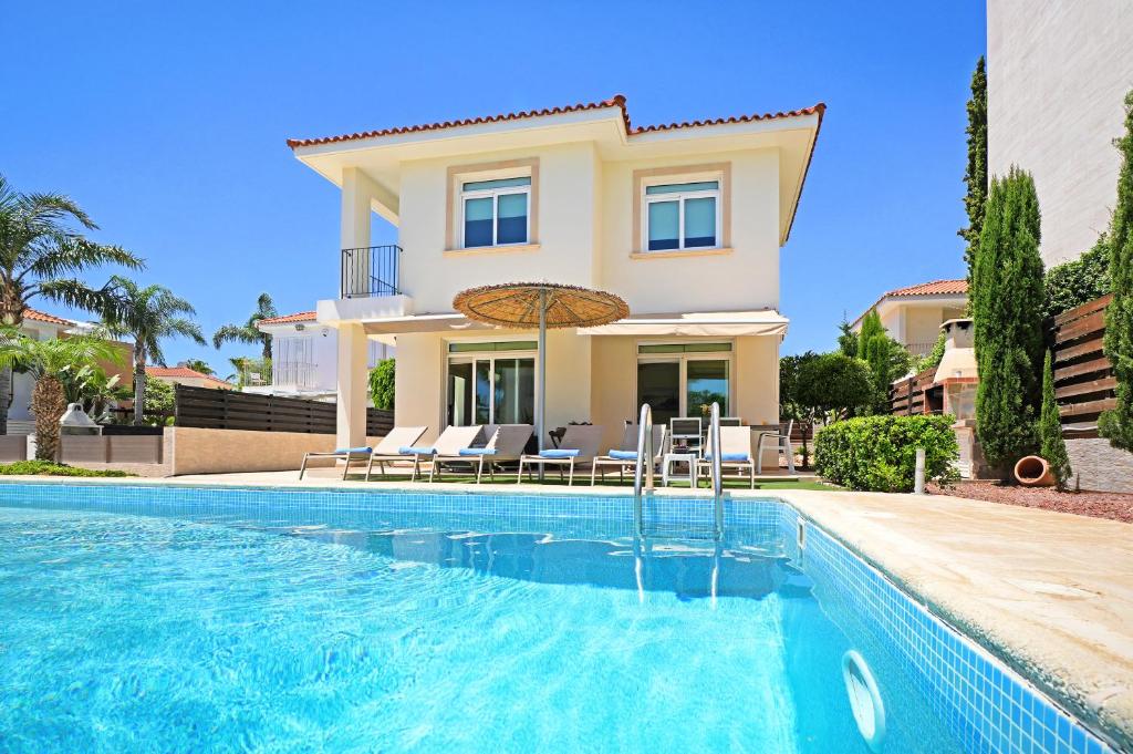 una villa con piscina frente a una casa en Villa Celine, en Protaras